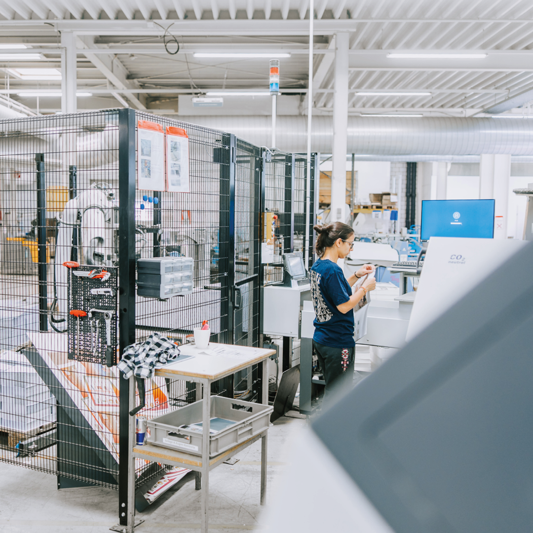 Das Bild zeigt die Produktion der VVA in Dornbirn. Es ist eine Mitarbeiterin in der Fertigung zu sehen, die gerade eine Kontrolle durchführt.